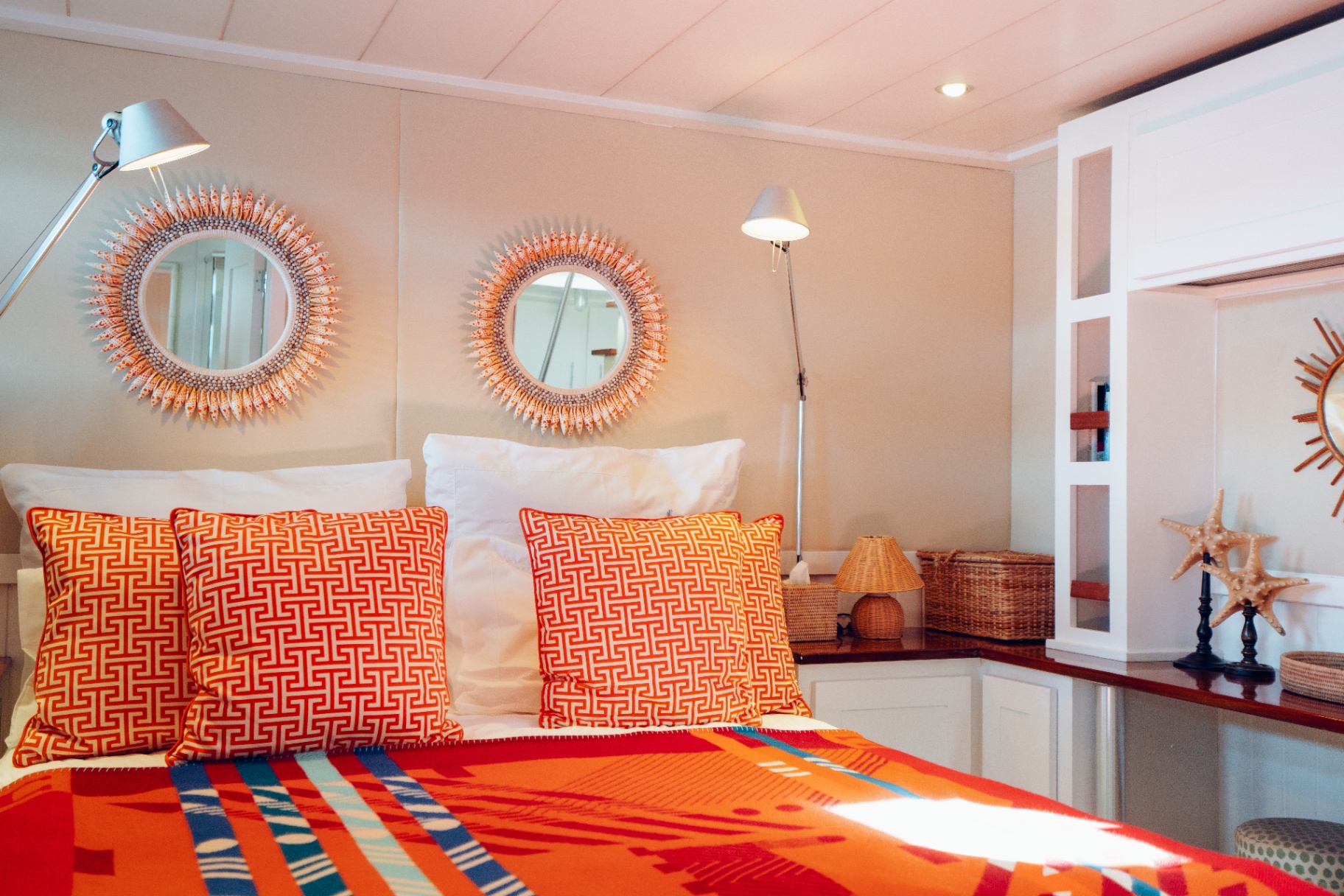 Cabin with orange Hermès cushions and shell sunburst mirrors